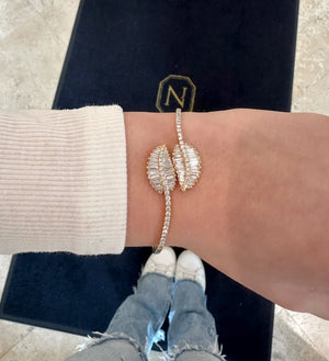Female model wearing Diamond Bypass Leaf Bangle - 14kt yellow gold 12.60 grams - 56 straight baguettes weighing 1.50 ct - 46 round brilliant cut diamonds weighing 0.83 ct