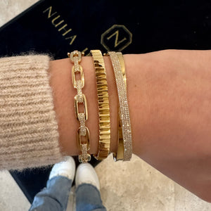 Female model wearing Diamond Bold Link Bangle Bracelet - 14K gold weighing 14.59 grams - 120 round diamonds totaling 0.45 carats