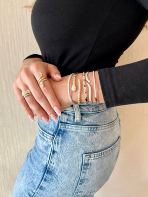 Female model wearing Diamond Medium Classic Bangle Bracelet -18K gold weighing 12.42 grams - 27 round diamonds totaling 1.53 carats