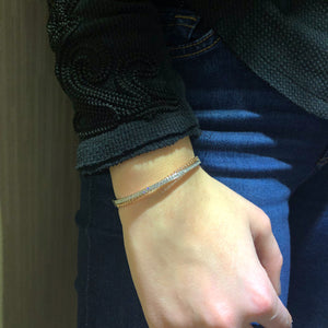 Female Model Wearing Diamond Two-Tone Crossover Bangle Bracelet -14K gold weighing 15.82 grams -39 round channel-set diamonds totaling .80 carats