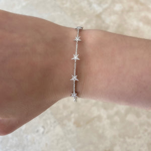 Female model wearing Dainty Diamond Star Bangle Bracelet -14k white gold weighing 8.28 grams -5 round bezel diamonds weighing 0.15 carats, and 98 round pave set diamonds weighing 0.27 carats