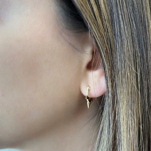 Female model wearing Diamond Spike Huggie Earrings - 14K yellow gold weighing 2.18 grams  - 20 round diamonds totaling 0.05 carats