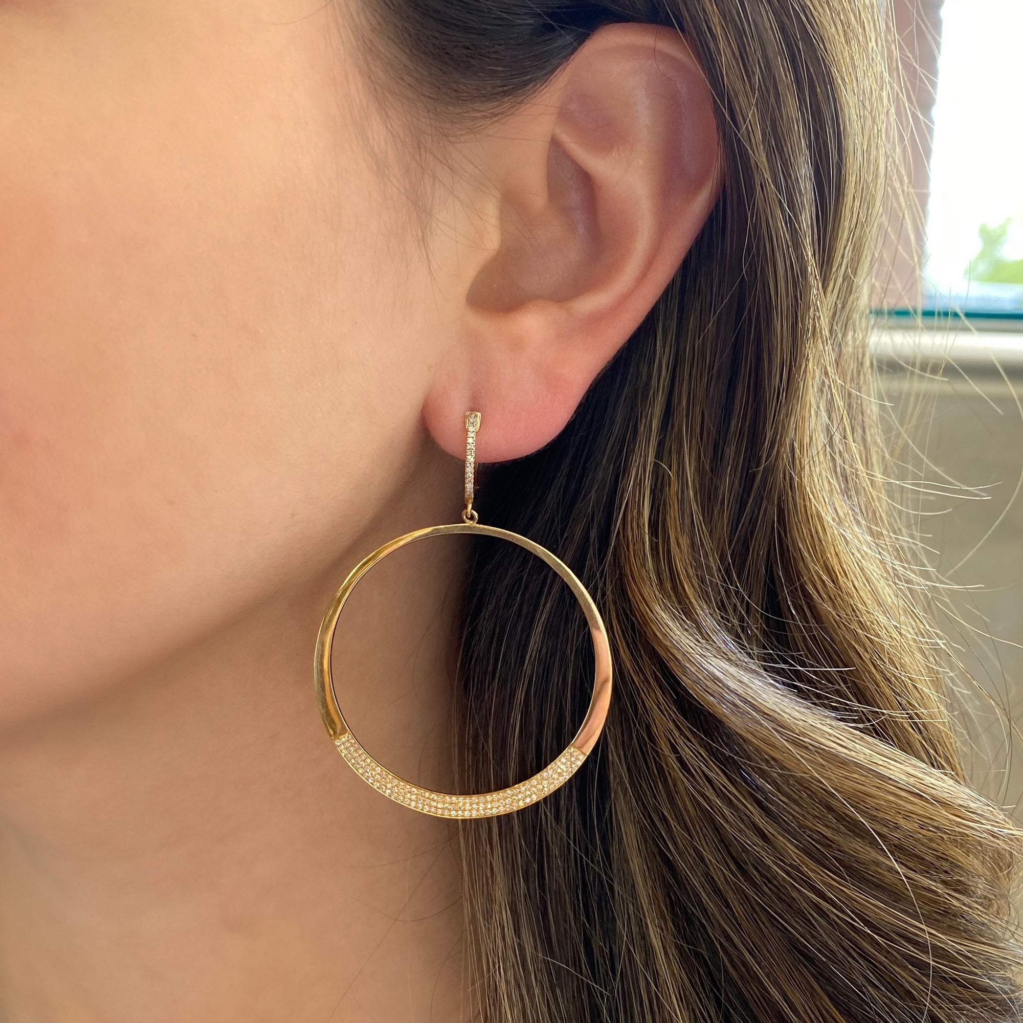 Circle Statement Earrings  These partial diamond hoops are composed of 14k gold, 9.66 grams, 284 round pave-set diamonds weighing .64 carats, making for a glamourous statement piece to amplify any look.