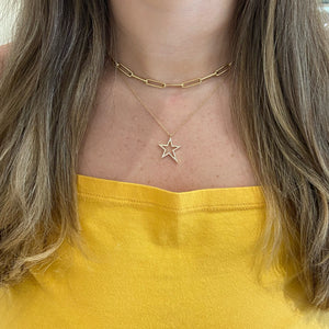 Female model wearing Diamond Asymmetrical Star Pendant Necklace - 14K gold weighing 2.23 grams. - 59 round diamonds 0.17 carats.