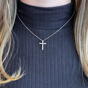 Female Model Wearing Diamond Classic Cross Pendant Necklace  -14K gold weighing 2.40 grams  -15 round prong-set brilliant diamonds totaling 0.44 carats