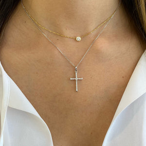 Female Model Wearing Diamond Skinny Cross Pendant Necklace  -14K gold weighing 2.85 grams  -20 round shared prong-set brilliant diamonds totaling 0.20 carats