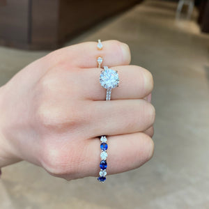 Female Model Wearing Sapphire & Diamond Eternity Ring - 18K gold weighing 2.67 grams - 8 round diamonds totaling 1.10 carats - 8 oval-shaped sapphires totaling 2.46 carats