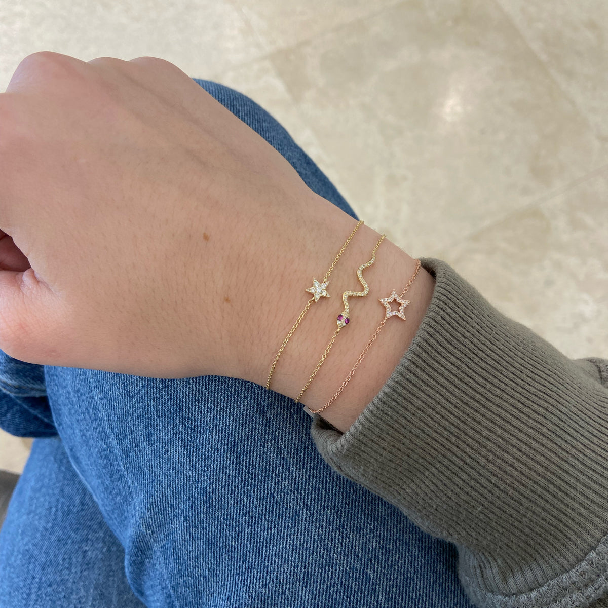 Female Model Wearing Emerald & Diamond Snake Fashion Bracelet - 14K gold weighing 1.37 grams - 35 round diamonds weighing 0.09 carats - 2 emeralds weighing 0.02 carats