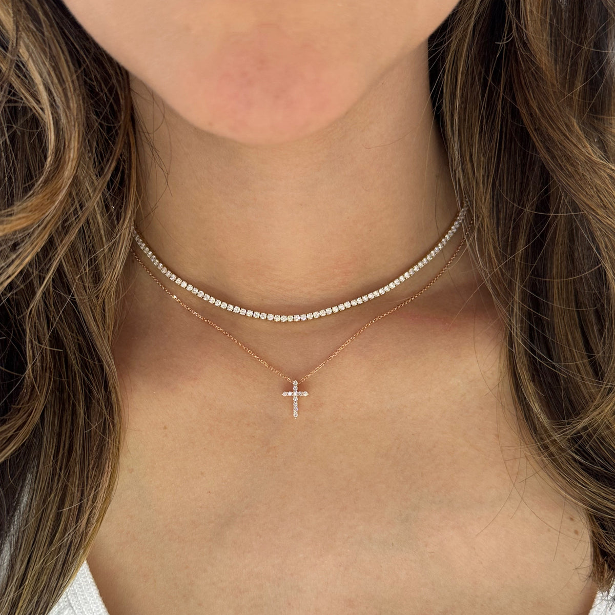 Female model wearing Diamond Small Cross Pendant - 14K yellow gold weighing 2.03 grams -11 round diamonds totaling 0.14 carats