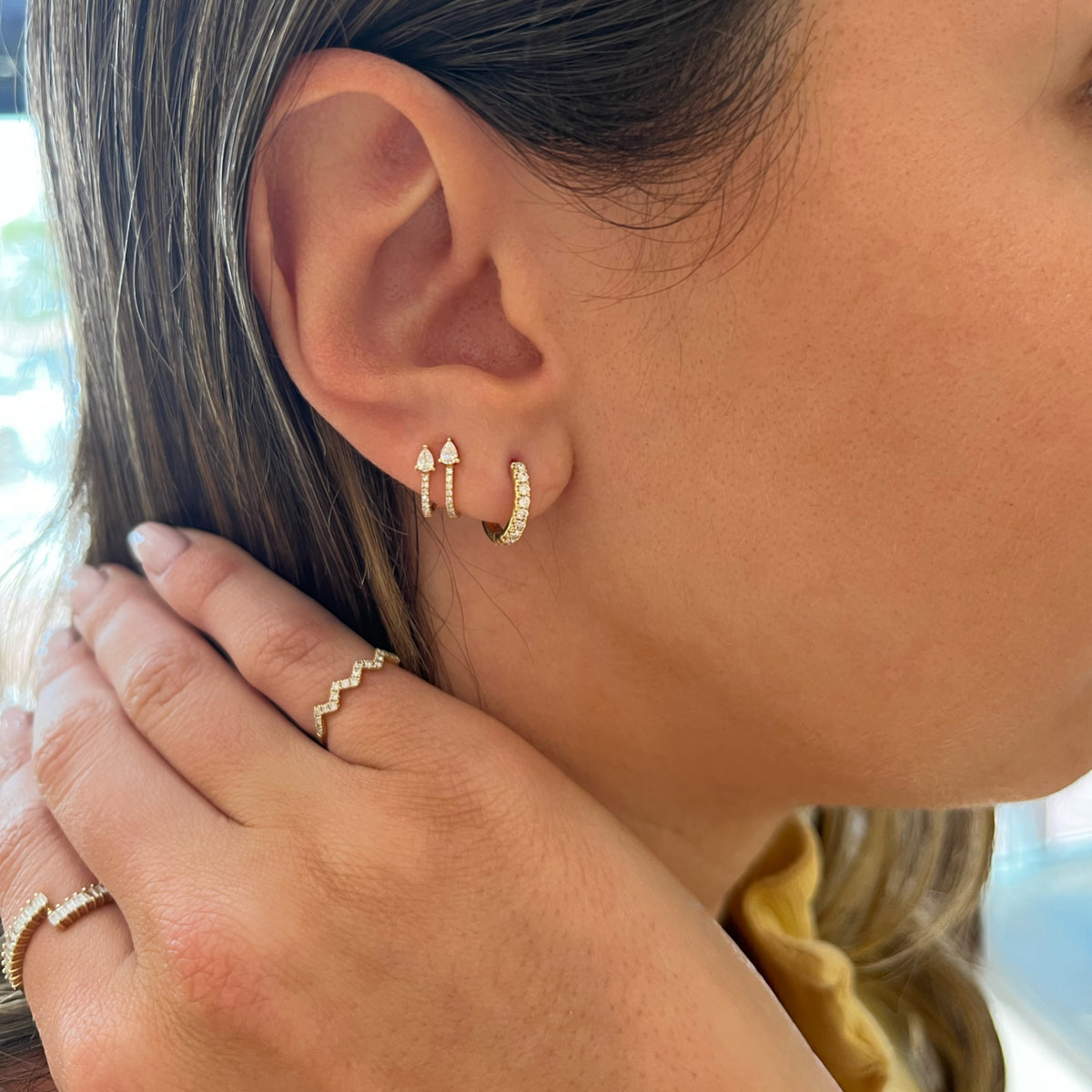 Female Model Wearing Diamond Small Classic Huggie Earrings - 18K gold weighing 2.29 grams - 18 round diamonds totaling 0.28 carats