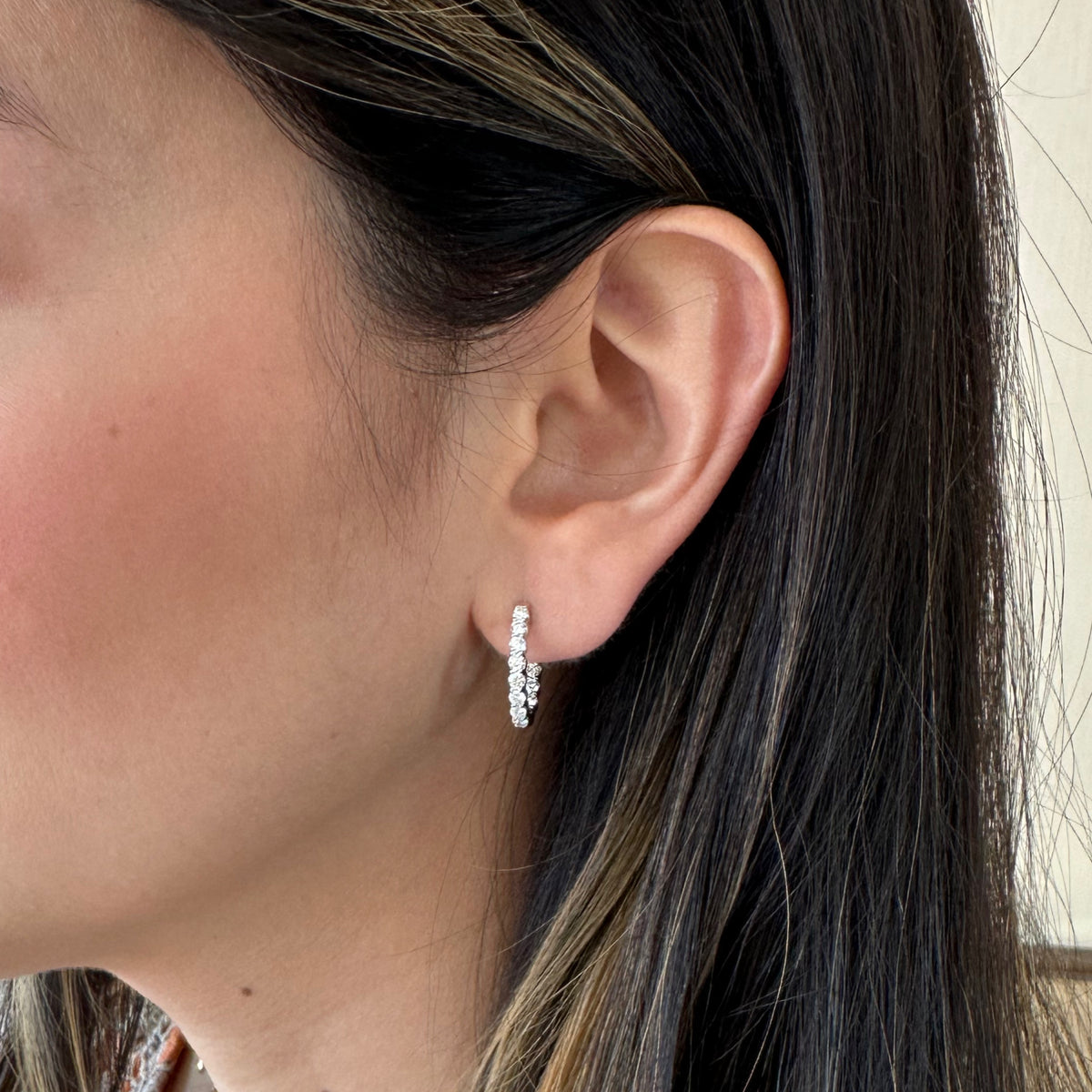 Female model wearing 1ct Diamond Interior & Exterior Huggie Earrings - 18K gold weighing 2.83 grams - 24 round diamonds weighing 1.05 carats