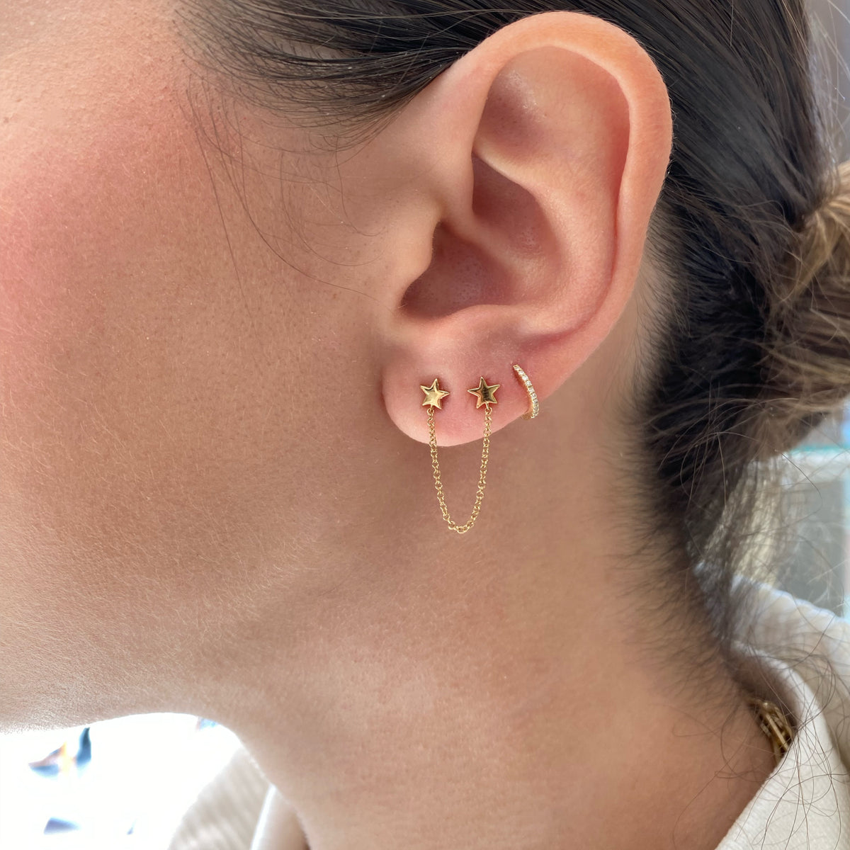 Female Model Wearing Diamond Petite Huggie Earrings - 14K gold weighing 0.85 grams - 20 round diamonds weighing 0.05 carats