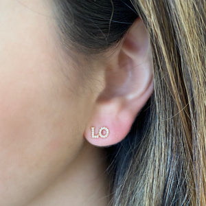 Female model wearing Diamond "LOVE" Stud Earrings - 14K gold weighing 0.91 grams - 41 round diamonds weighing 0.10 carats