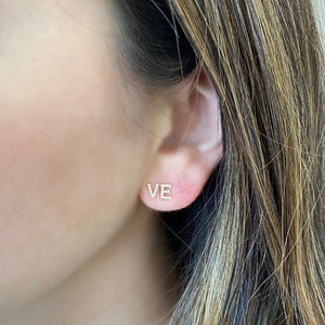 Female model wearing Diamond "LOVE" Stud Earrings - 14K gold weighing 0.91 grams - 41 round diamonds weighing 0.10 carats
