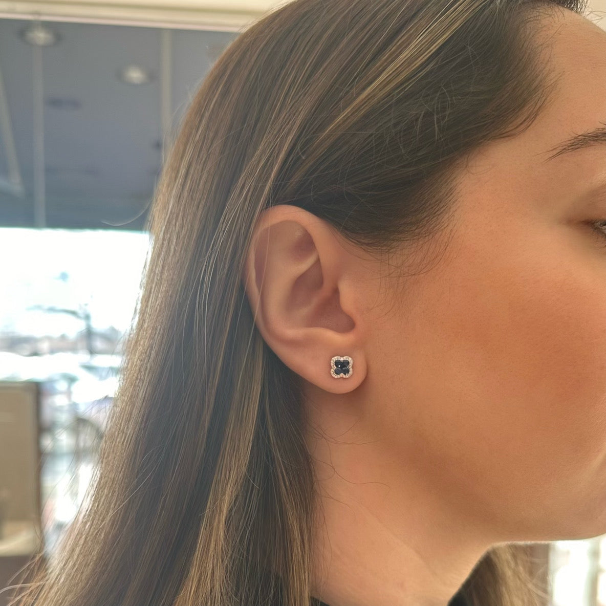 Female model wearing Sapphire & Diamond Clover Stud Earring - 18K gold weighing 2.41 grams - 48 round diamonds weighing 0.13 carats - 8 sapphires weighing 0.54 carats - 2 sapphires weighing 0.06 carats
