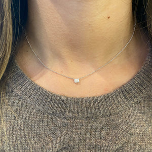 Female model wearing Emerald Illusion Pendant Necklace - 14K white gold weighing 2.24 grams - 4 round diamonds weighing 0.01 carats - 5 slim baguettes weighing 0.11 carats