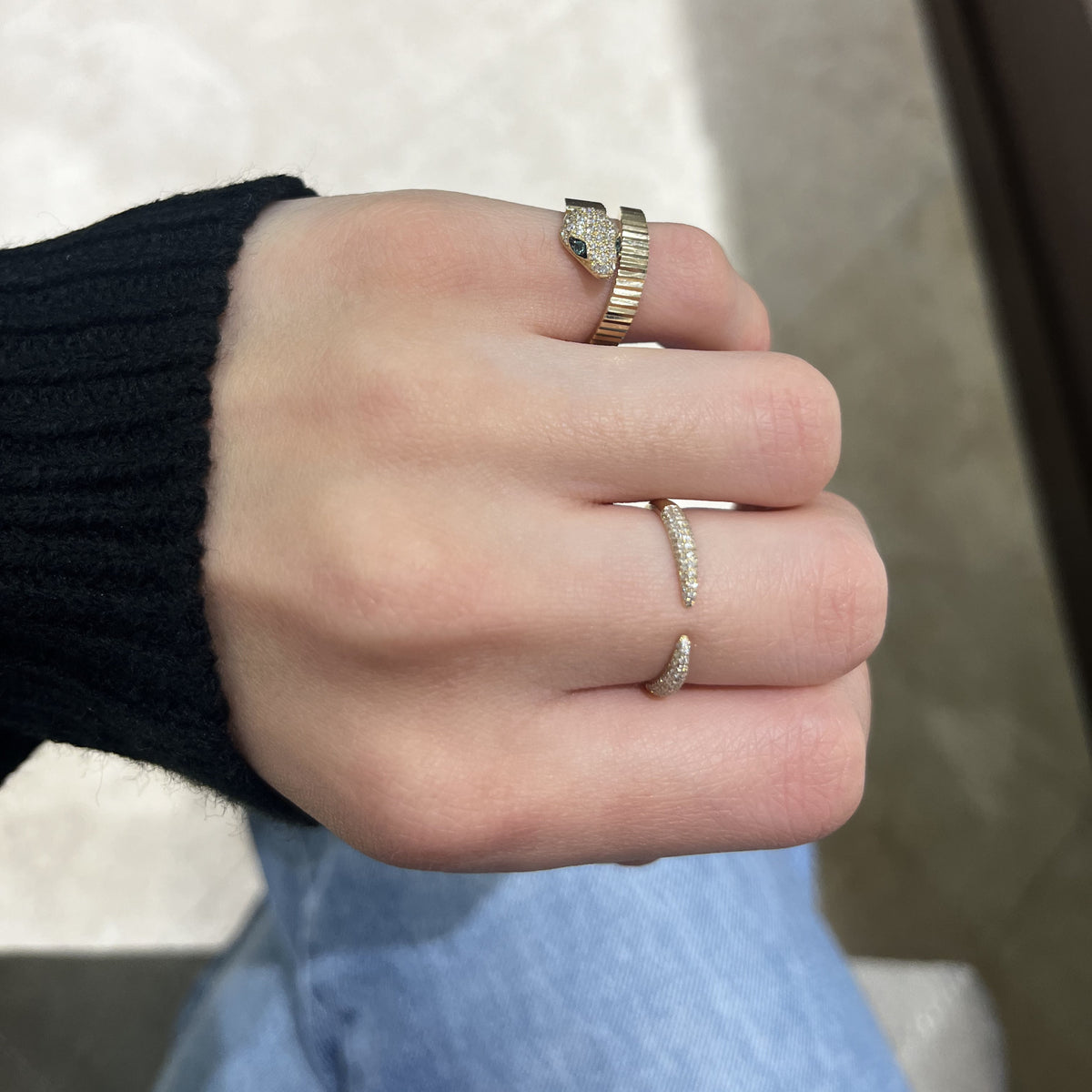 Female Model Wearing Emerald & Diamond Pleated Gold Snake Ring - 14K gold weighing 3.85 grams - 39 round diamonds weighing 0.23 carats - 2 emerald-cut diamonds weighing 0.04 carats
