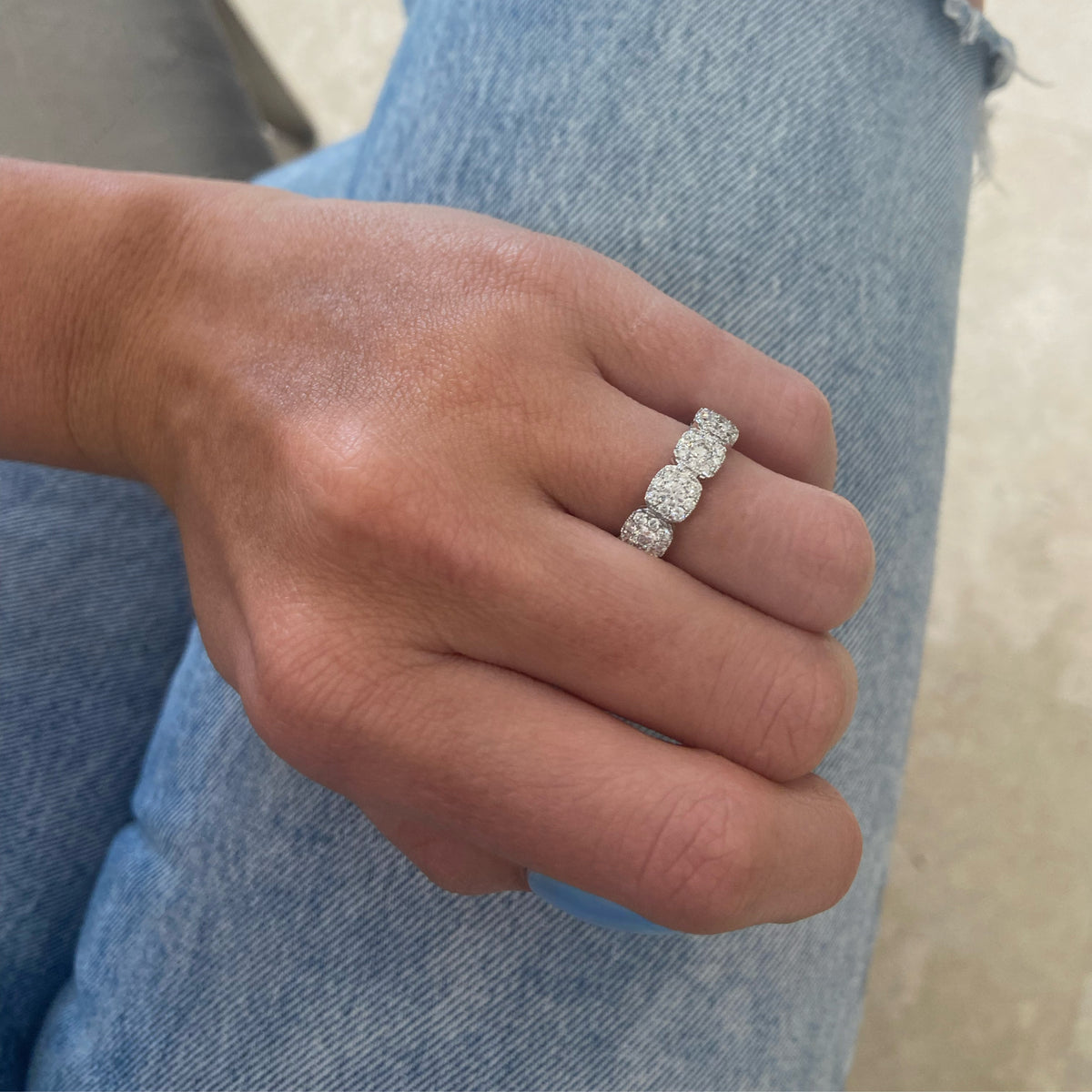 Female model wearing Diamond cushion-style halo eternity ring -18K gold weighing 4.18 grams  -11 round diamonds totaling 0.98 carats  -88 round pave-set diamonds totaling 1.30 carats