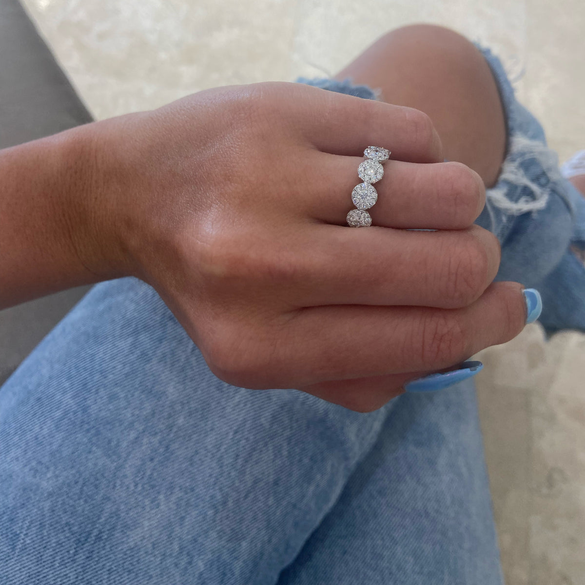 Female model wearing Diamond halo eternity ring -18K gold weighing 3.96 grams  -11 round diamonds totaling 1.18 carats  -99 round pave-set diamonds totaling 1.06 carats