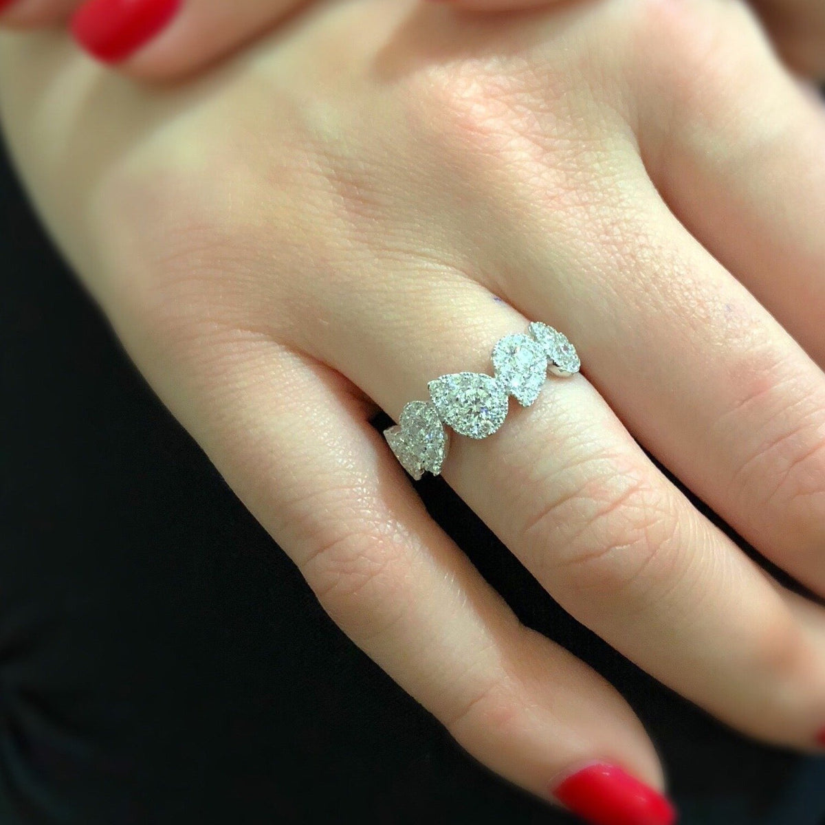 Female Model Wearing Diamond Stagggerd Pear-shaped Halo Ring  -18k gold, 3.21 grams  -50 round shared prong-set diamonds .69 carats  -5 round diamonds .52 carats.  Size 8 mm width approx.