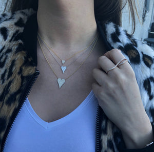 Female model wearing Diamond Small Elongated Heart Necklace  -14K yellow gold weighing 1.95 grams  -73 round pave set diamonds totaling 0.21 carats.