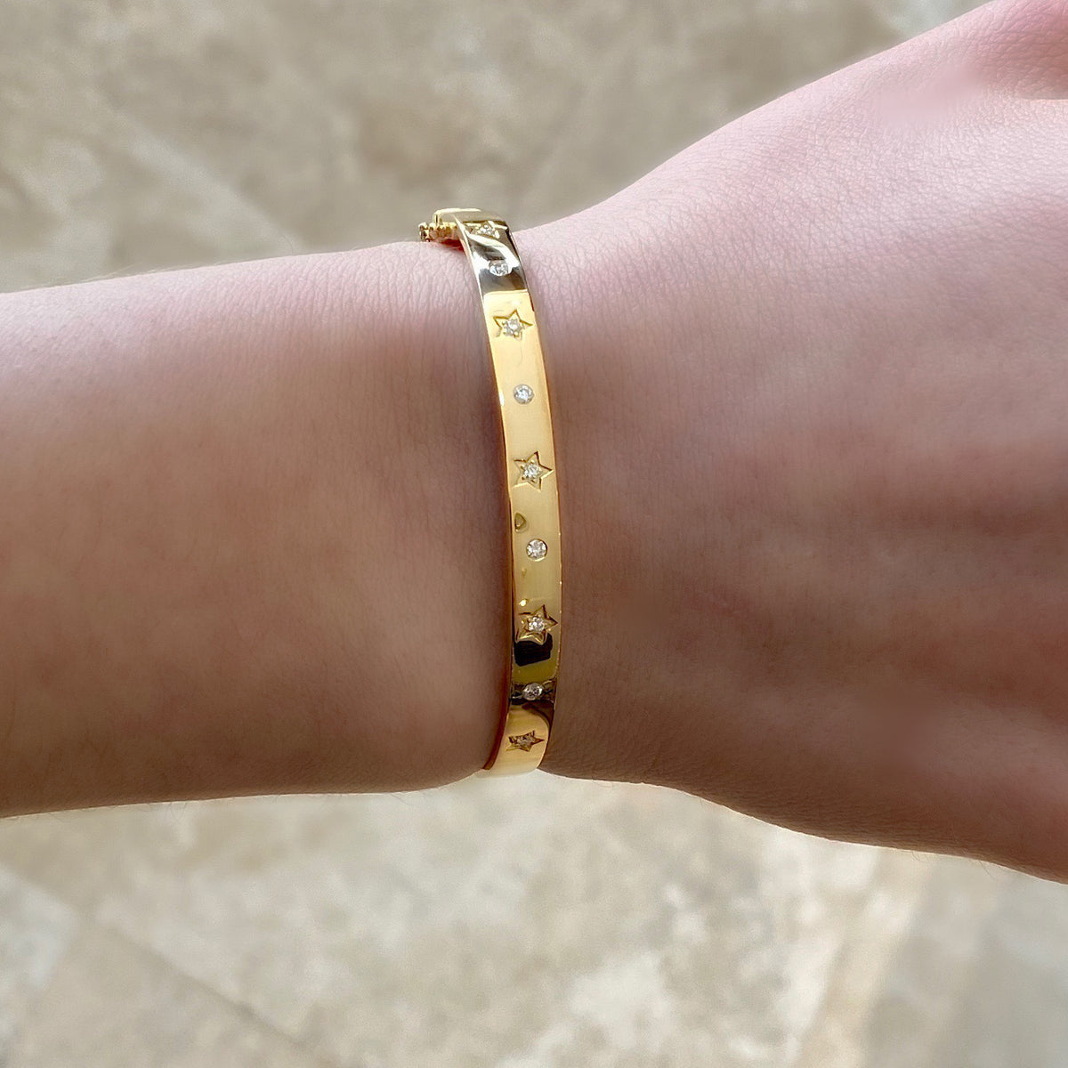 Female Model Wearing Diamond Stars & Circles Bangle  - 14K gold weighting 11.53 grams.  - 18 round diamonds totaling 0.37 carat weight.