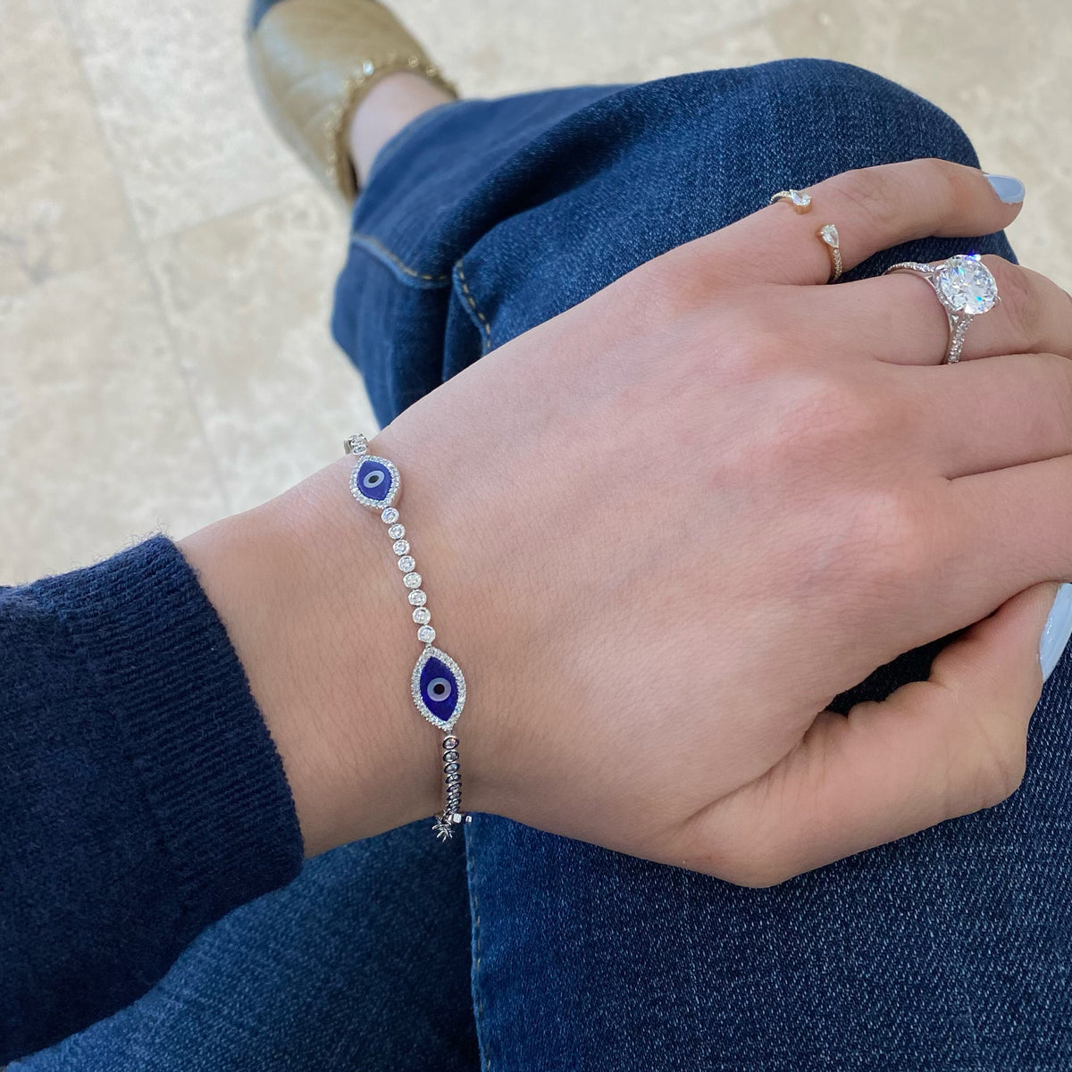 Female model wearing Bezel-Set Diamond Evil Eye Bracelet -14K gold weighing 8.02 grams -144 round diamonds totaling 0.81 carats -4 lapis totaling 1.17 carats