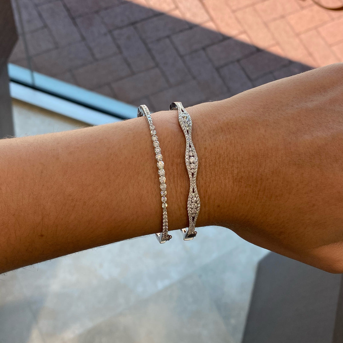 Female model wearing Graduated Diamond Bangle Bracelet - 18K gold weighing 10.79 grams - 22 round diamonds totaling 0.39 carats - 13 round diamonds totaling 0.91 carats