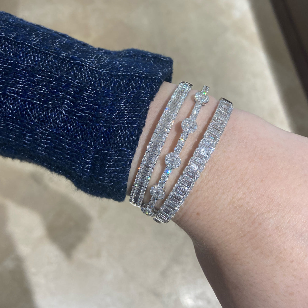 Female model wearing Halo Diamond Bangle Bracelet - 18K gold weighing 14.48 grams  - 23 round diamonds weighing 2.08 carats  - 45 round diamonds weighing 0.53 carats