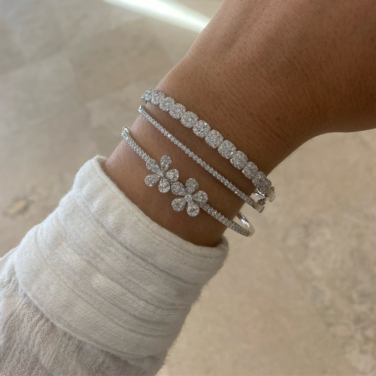 Female Model Wearing Diamond Double Flower Bangle - 18K gold weighing 16.15 grams  - 10 pear-shaped diamonds weighing 1.07 grams  - 81 round diamonds weighing 0.84 carats