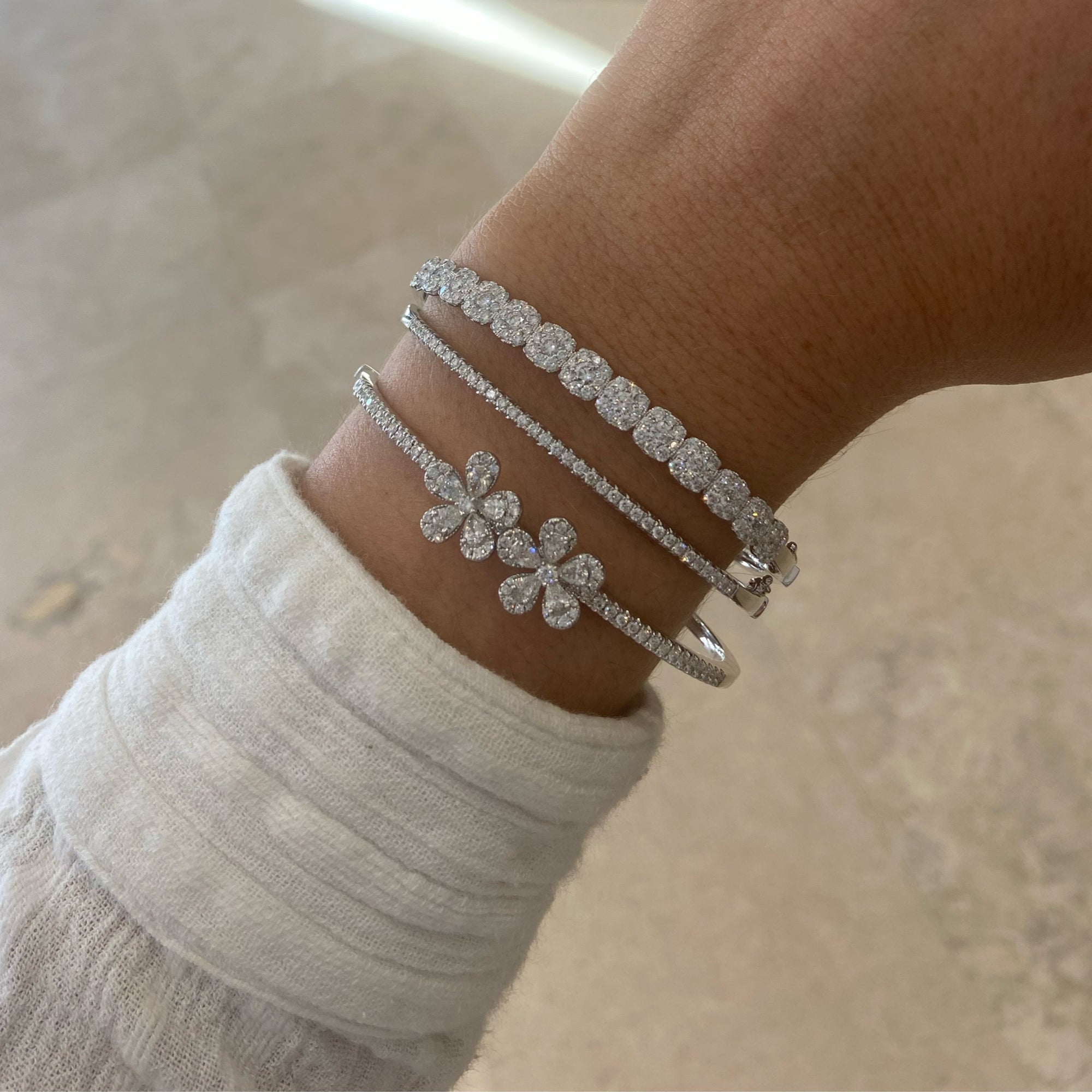 Solid 18K white gold weighing 12.93 grams featuring 104 round diamonds weighing 1.58 carats and 13 round diamonds weighing 0.99 carats Halo Diamond Bangle Bracelet | Nuha Jewelers