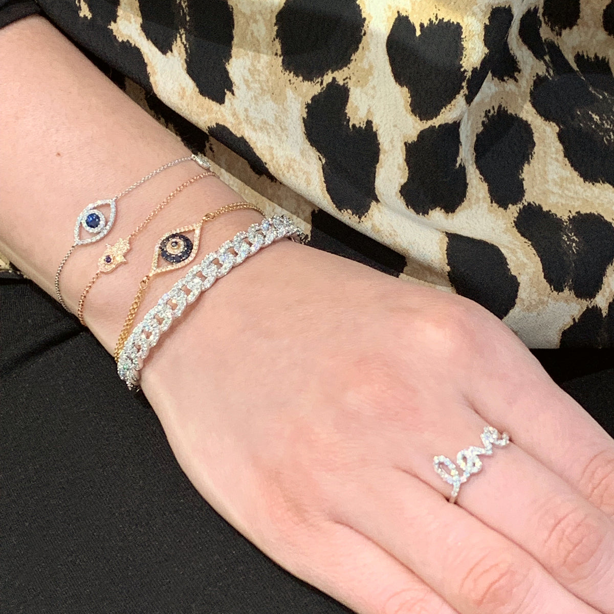 Female model wearing Diamond & Sapphire Evil Eye Bracelet -14K gold weighing 2.32 grams -46 round diamonds totaling 0.11 carats -11 sapphires totaling 0.35 carats