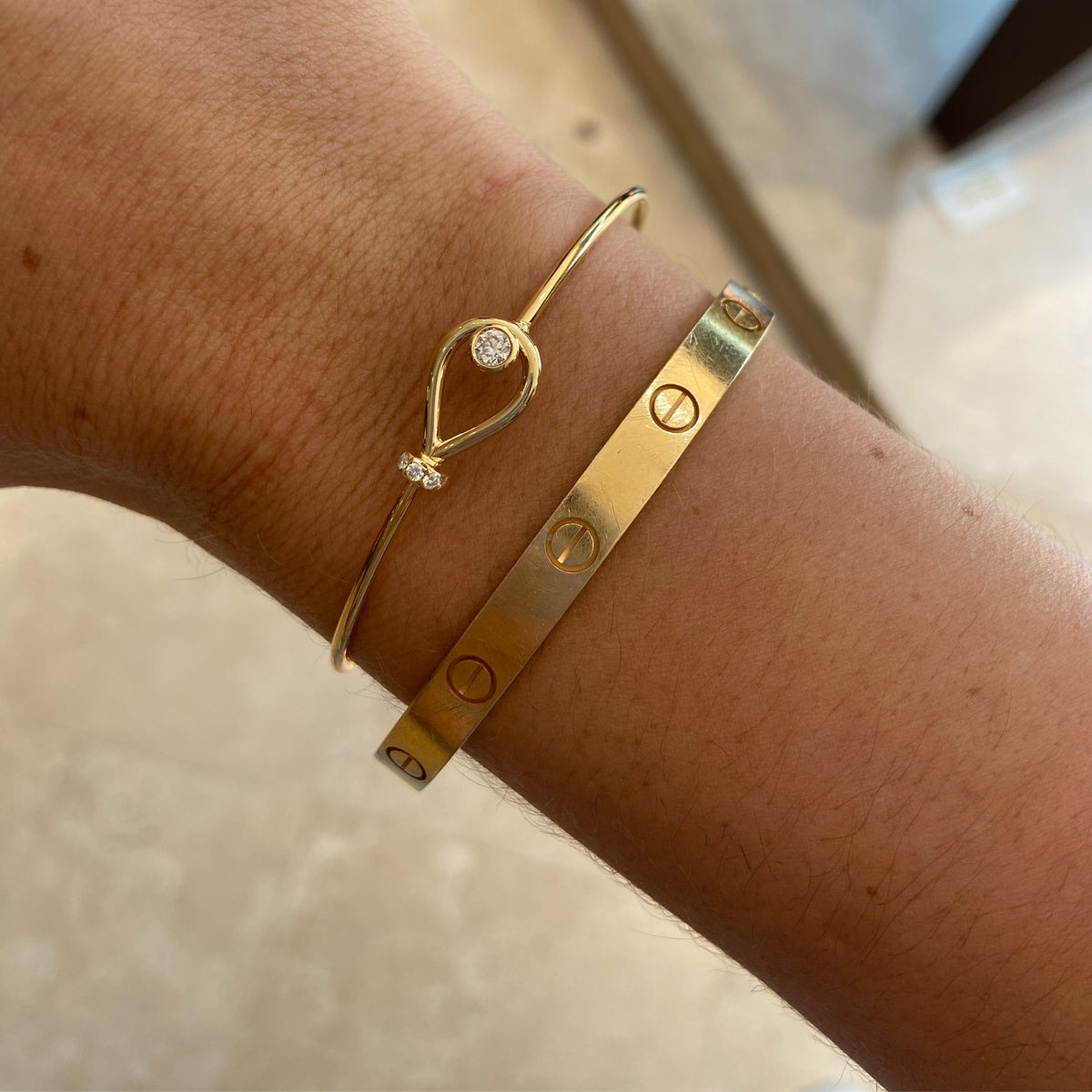 Female Model Wearing Diamond Loop Bangle Bracelet  - 18K gold weighing 4.43 grams  - 6 round diamonds totaling 0.22 carats