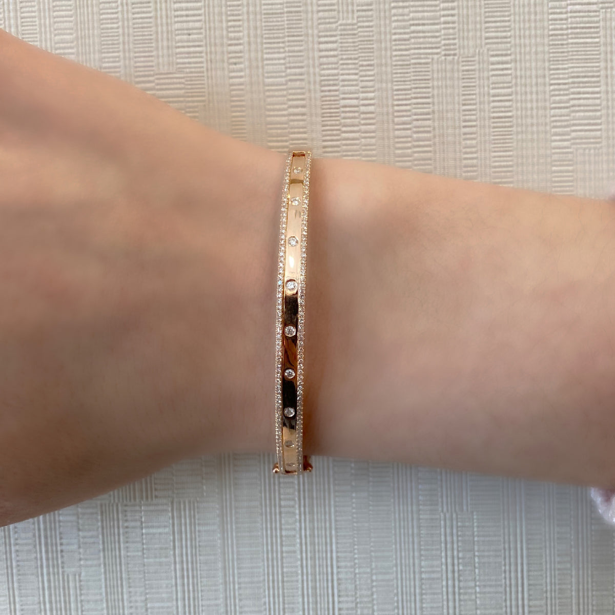 Female model wearing Bezel-Set & Pave Diamond Slim Bangle Bracelet -14K gold weighing 10.87 grams -9 round bezel set diamonds totaling 0.30 carats -160 round pave set diamonds totaling 0.45 carats