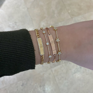 Female model wearing Diamond ID Bracelet with Paperclip Chain - 14K gold weighing 3.21 grams - 26 round diamonds totaling 0.07 carats