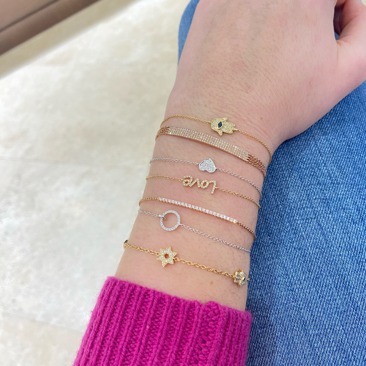 Female model wearing Diamond Open Circle Bracelet -14K gold weighing 1.05 grams -23 round diamonds totaling .06 carats