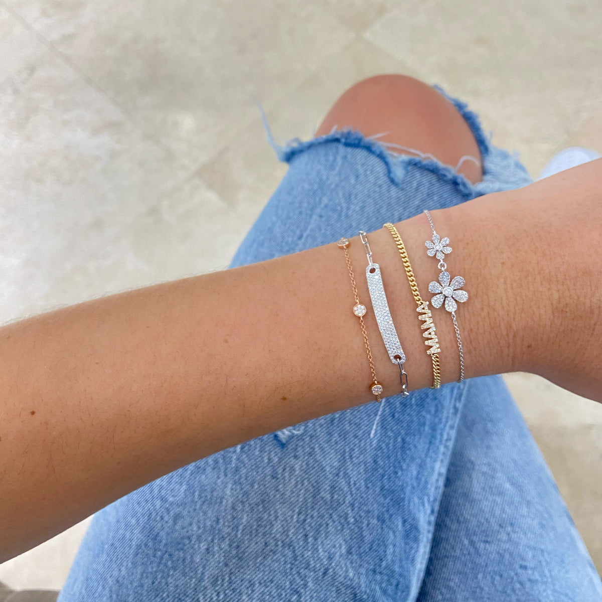 Female model wearing Diamond Double Daisy Bracelet - 14K gold weighing 2.50 grams - 2 round diamonds totaling 0.06 carats - 84 round diamonds totaling 0.28 carats