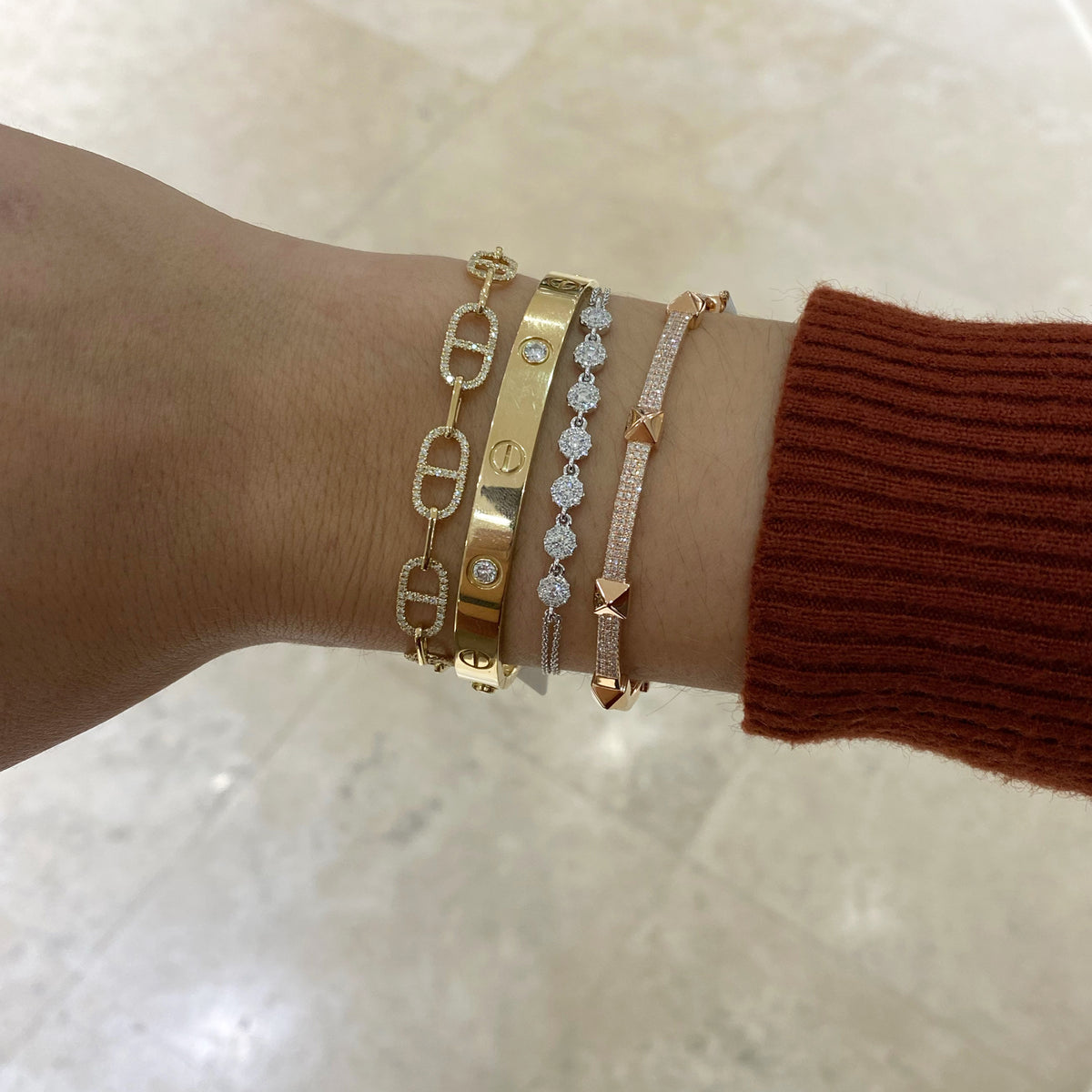 Female model wearing Diamond Halo Cable Chain Bracelet - 14K gold weighing 3.05 grams - 7 round diamonds totaling 0.28 carats - 70 round diamonds totaling 0.23 carats