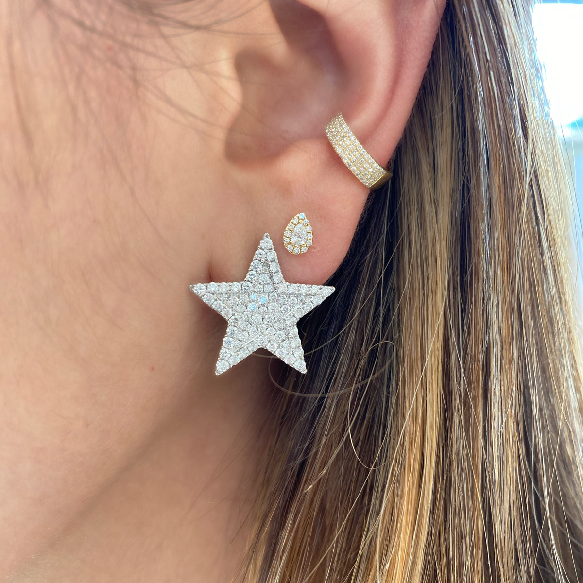 Female model wearing Diamond Teardrop Stud Earrings - 14K gold weighing 1.10 grams - 24 round diamonds totaling 0.08 carats - 2 pear-shaped diamonds totaling 0.16 carats