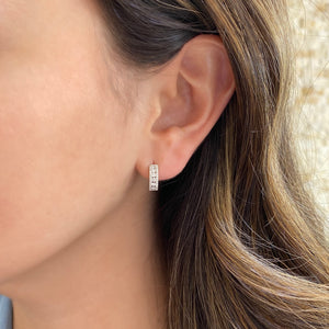 Female model wearing Diamond triple-row huggie earrings -18K gold weighing 2.93 grams  -68 round diamonds totaling 0.47 carats