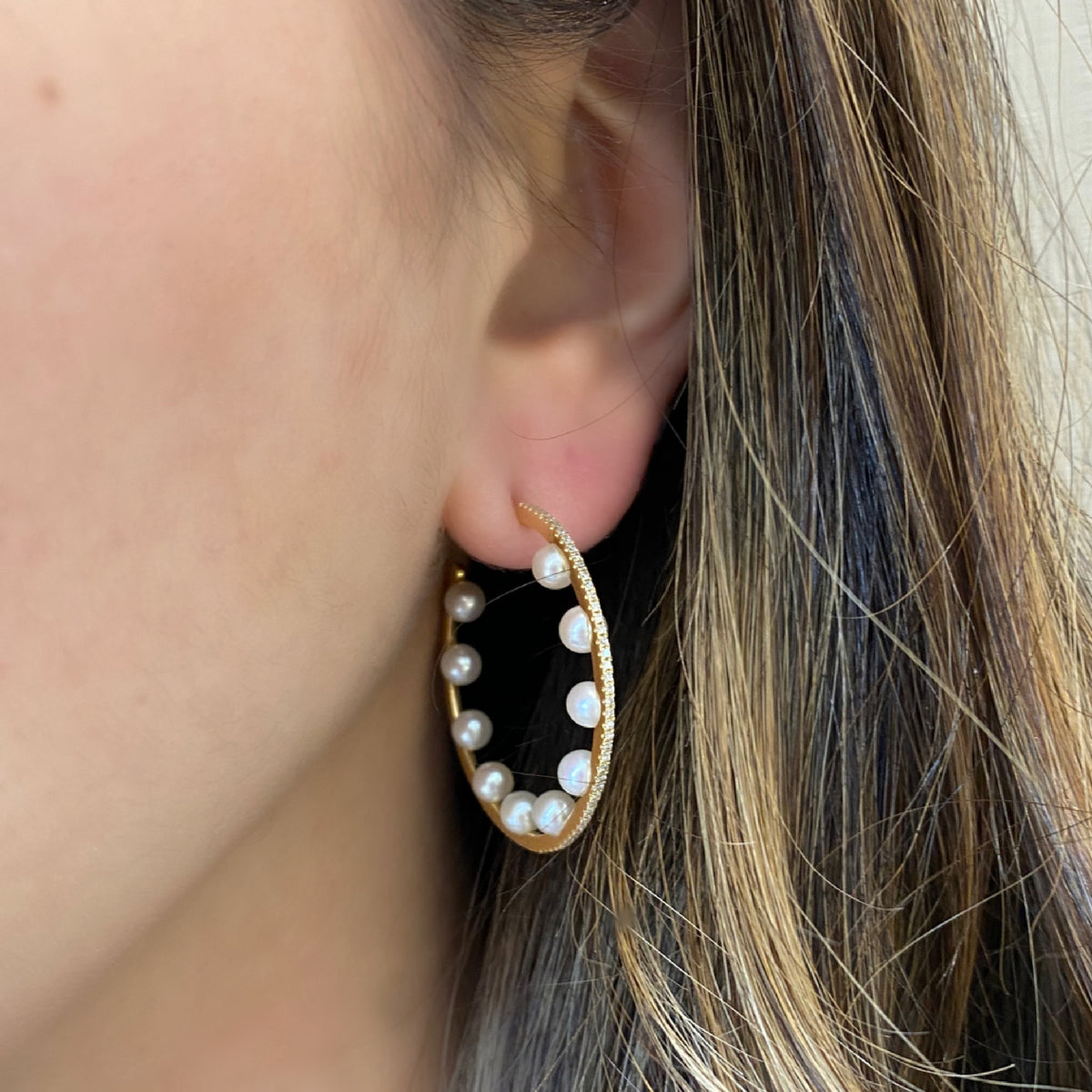 Female model wearing Pearl & diamond open hoop earrings -14K gold weighing 4.29 grams  -168 round diamonds totaling 0.46 carats  -20 pearls