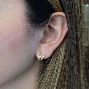 Female model wearing Diamond butterfly huggie earrings - 14K gold weighing 2.08 grams  - 80 round diamonds totaling 0.18 carats