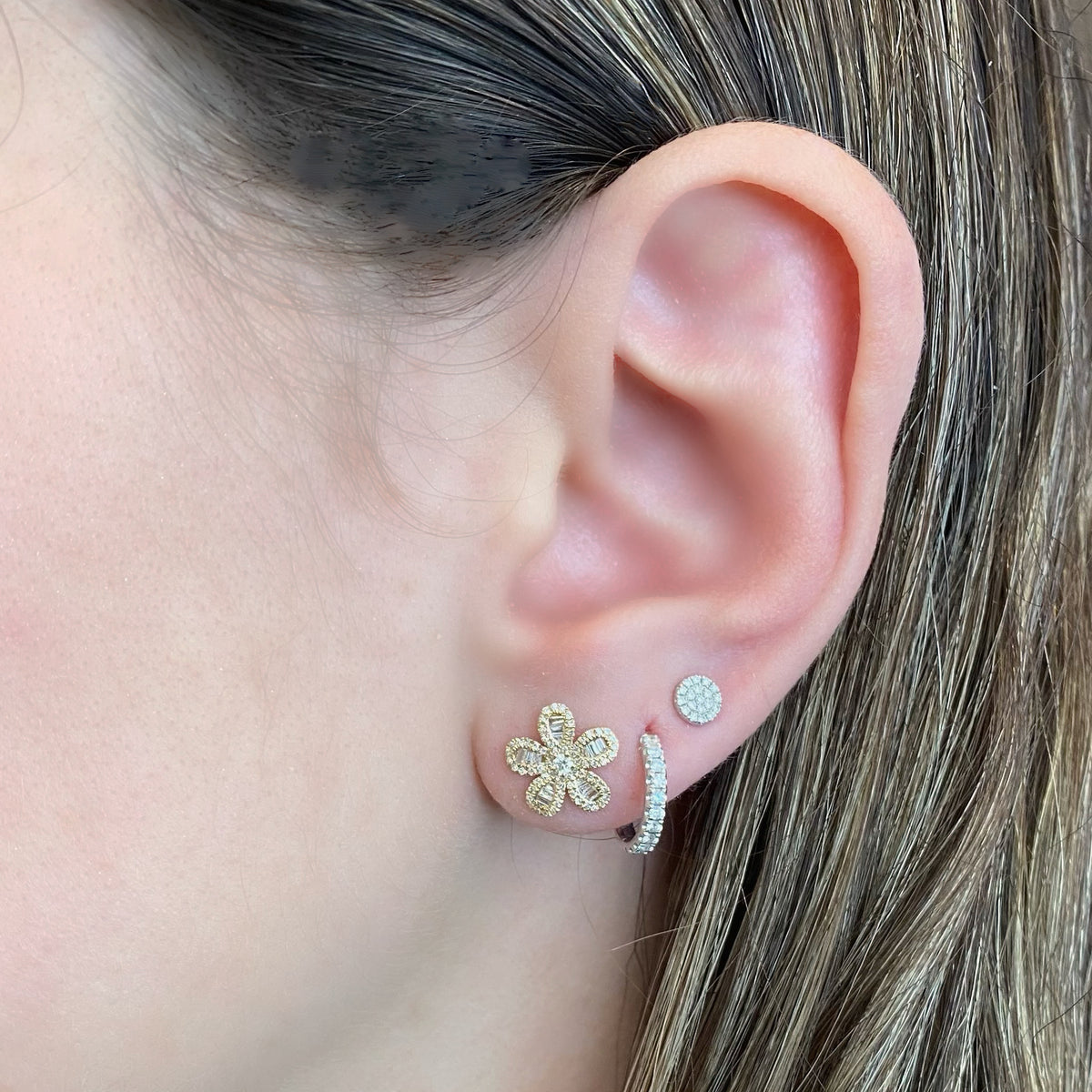 Female model wearing Diamond Baguette Daisy Stud Earrings - 14K gold weighing 1.78 grams  - 132 round diamonds totaling 0.21 carats  - 30 tapered baguettes totaling 0.18 carats