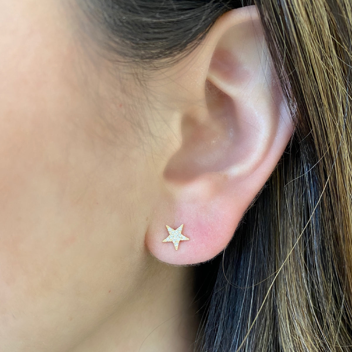 Female model wearing Diamond Star & Lightning Bolt Stud Earrings - 14K yellow gold weighing 0.90 grams - 23 round diamonds totaling 0.06 carats.