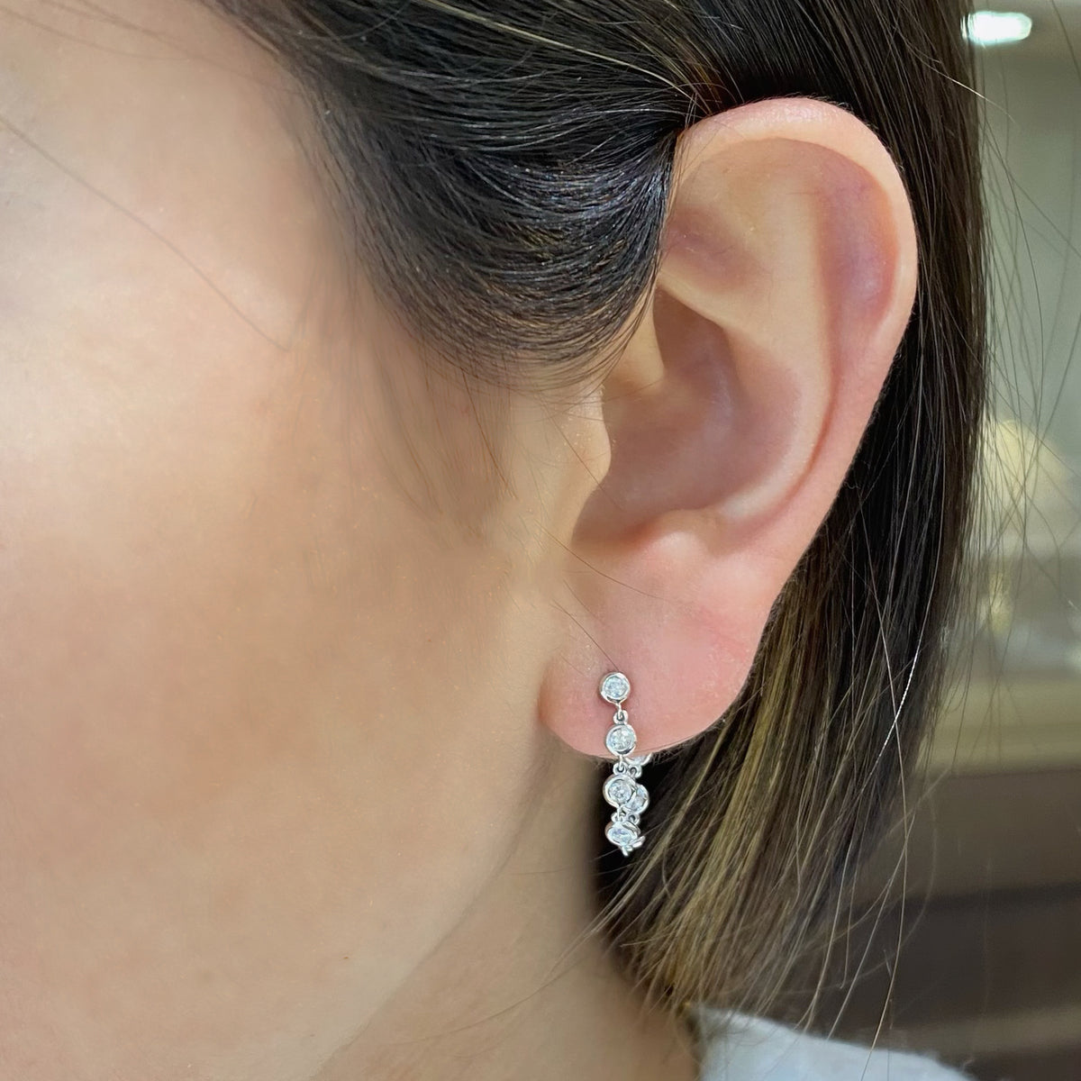 Female model wearing Diamond bezel front-back earrings- 14K gold weighing grams 1.84 grams - 14 round diamonds totaling .37 carats