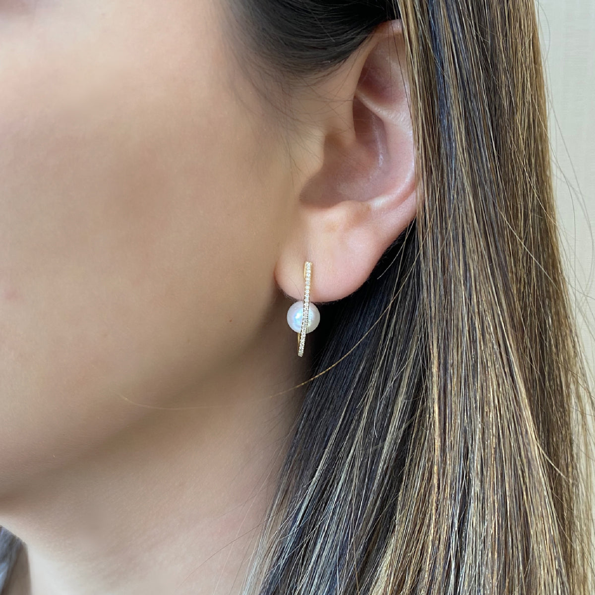 Female model wearing Diamond hoop earrings with pearls - 14 kt gold weighing 1.90 grams  - 48 round diamond with a 0.11 total carat weight  - 2 pearls