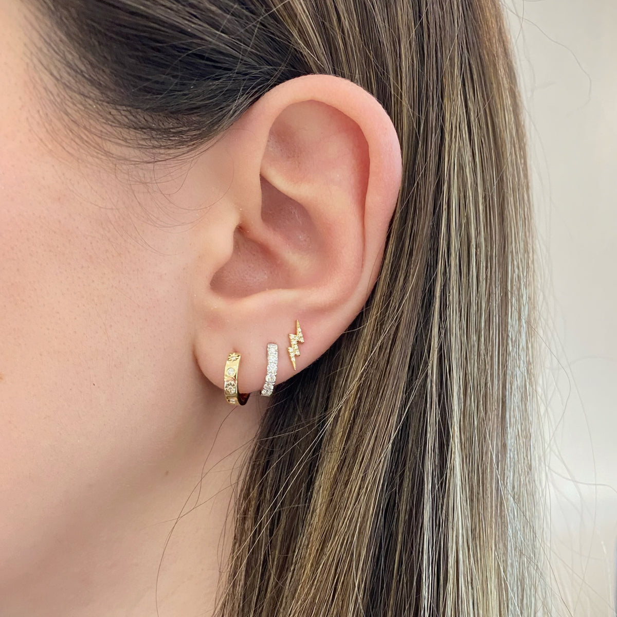 Female model wearing Diamond Star & Moon Huggies - 14K yellow gold weighing 2.29 grams  - 10 round diamonds weighing 0.08 carats