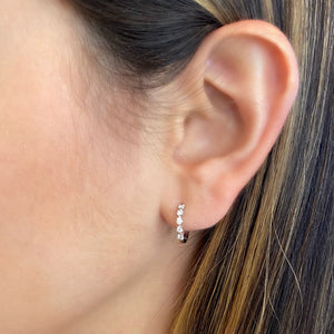Female Model Wearing Diamond 5-Stone Huggie Earrings - 14K gold weighing 1.54 grams  - 10 round diamonds totaling 0.16 carats