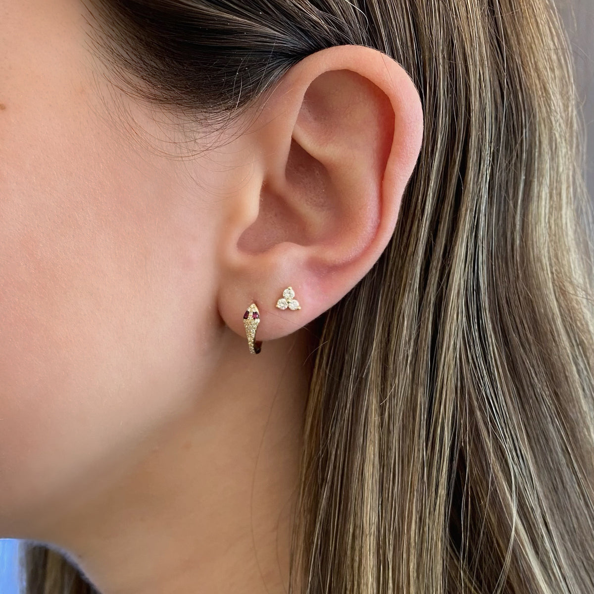 Female model wearing Ruby & diamond serpent huggie earrings - 14K gold weighing 1.63 grams  - 42 round diamonds totaling 0.12 carats  - 4 rubies totaling 0.05 carats