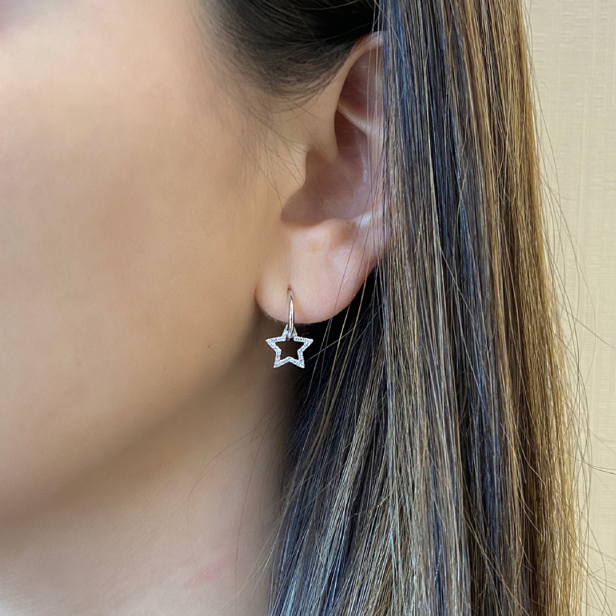 Female Model Wearing Gold Hoop Earrings With Diamond Star Cutouts - 14K gold weighing 1.88 grams    - 54 round diamonds weighing 0.12 carats total